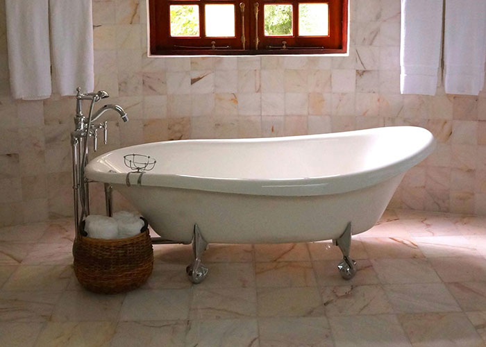 Clawfoot bathtub in a tiled bathroom with natural light, illustrating genius cleaning hacks inspired by laziness.