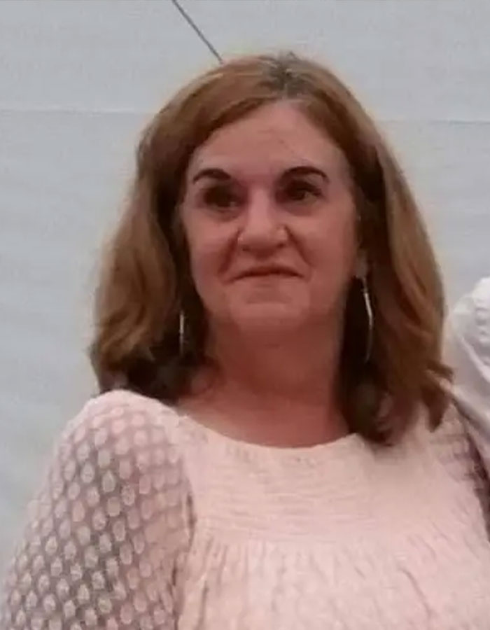 Woman linked to missing woman&rsquo;s body discovered in garage case, posing indoors with light-colored top and hoop earrings.