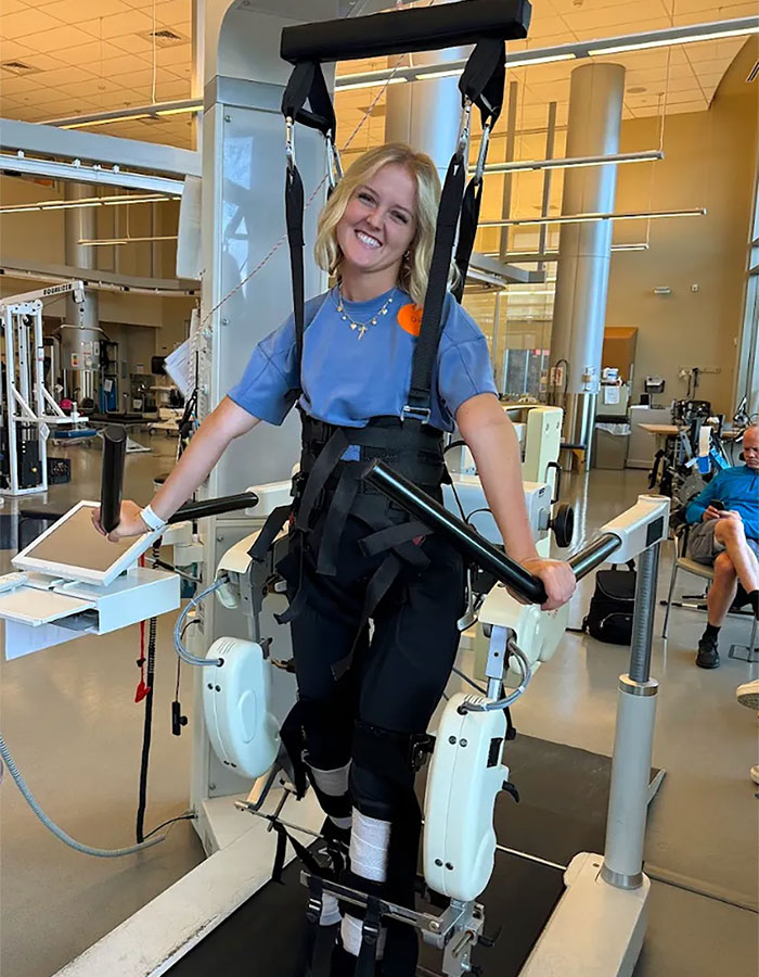 Young girl undergoing physical therapy using a robotic gait trainer after paralysis caused by a basic mistake.