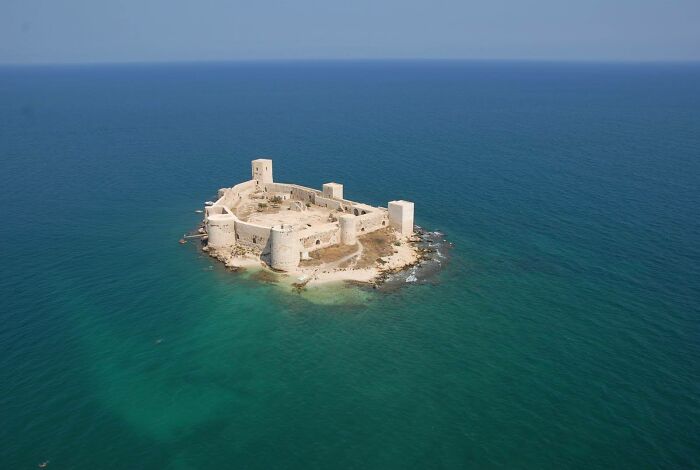 Aerial view of an ancient fortress on a small island surrounded by blue sea, showcasing fascinating archeology finds.