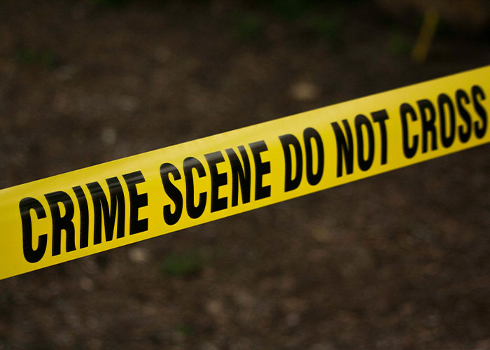 Yellow crime scene tape with black text reading crime scene do not cross, marking a police investigation area.