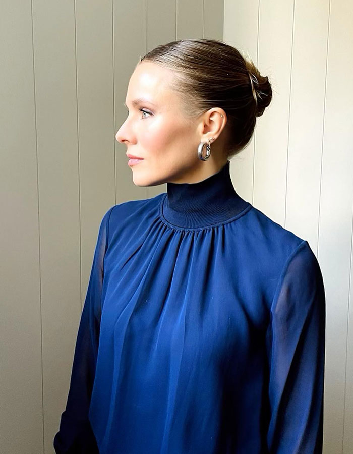 Kristen Bell in a blue blouse and hoop earrings, looking sideways, relating to Fox News religious podcast backlash. Kristen Bell in a blue blouse and hoop earrings, looking sideways, relating to Fox News religious podcast backlash.