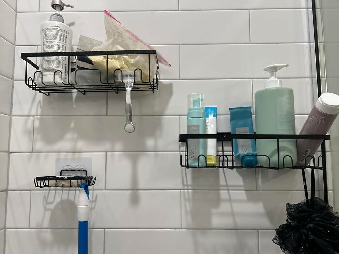 Black metal shower shelves holding toiletries on white tiled wall, showcasing cozy finds for a comfortable house feel.