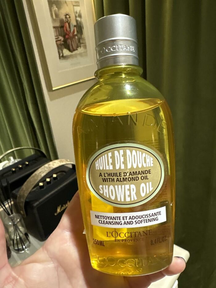 Hand holding a L'Occitane almond oil shower oil bottle, featured in Black Friday restocking beauty deals.