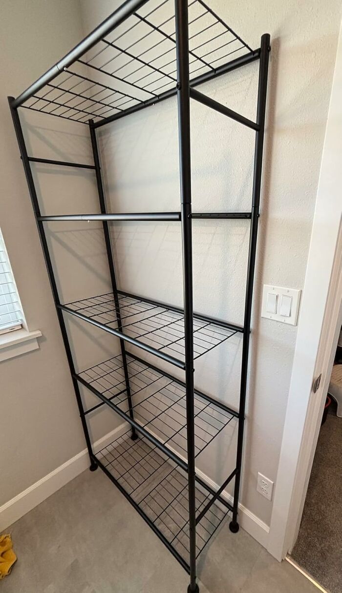Black metal shelving unit with five wire grid shelves placed against a beige wall for 11.11 deals storage ideas.
