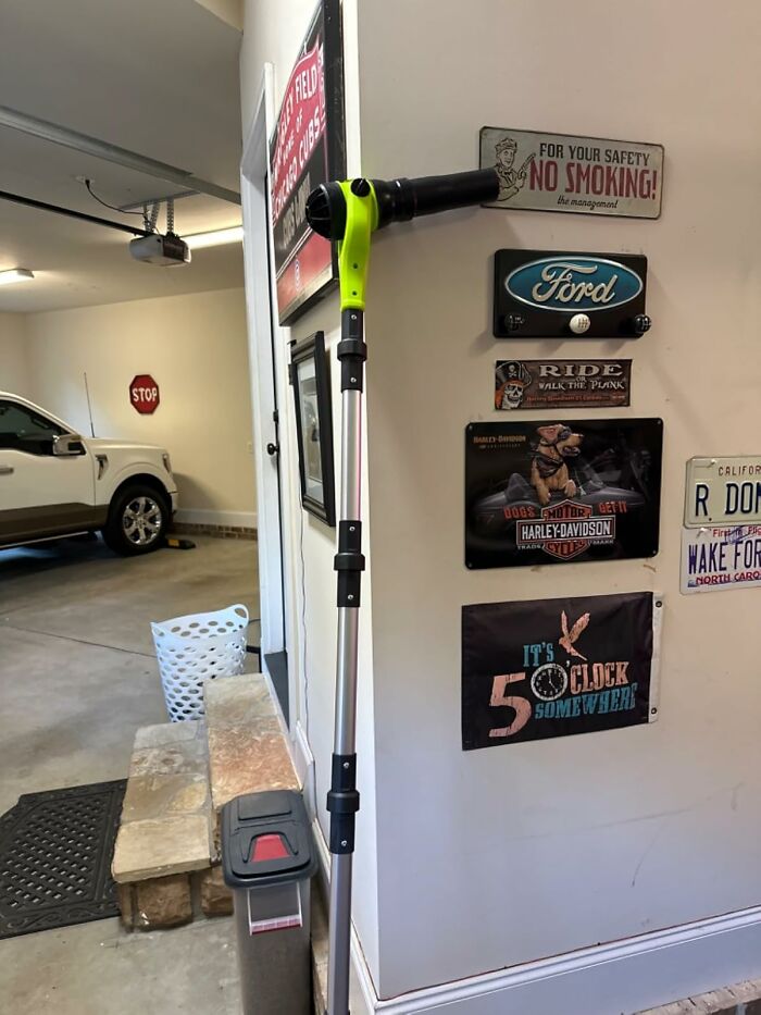 Garage interior with a car, vintage signs, and a leaf blower, highlighting tools for your garden before the first freeze.