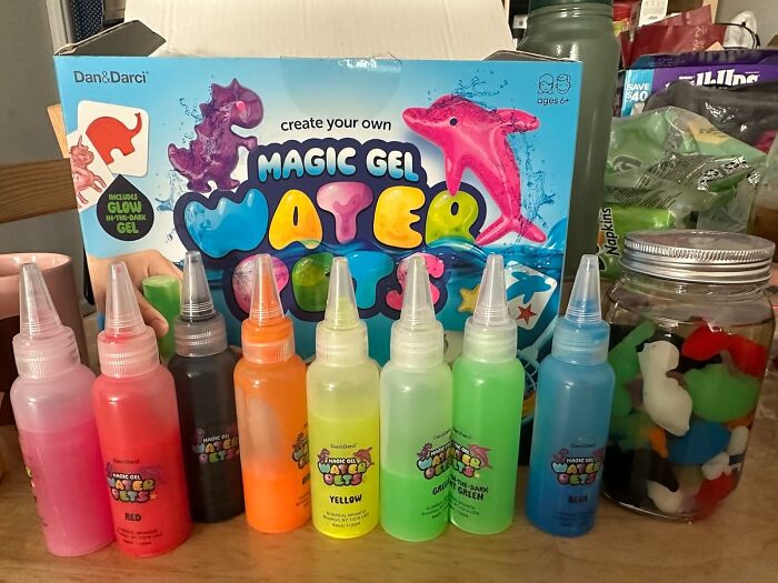 Bottles of colorful magic gel water crystals and kit for creative DIY stocking stuffers on a kitchen counter.
