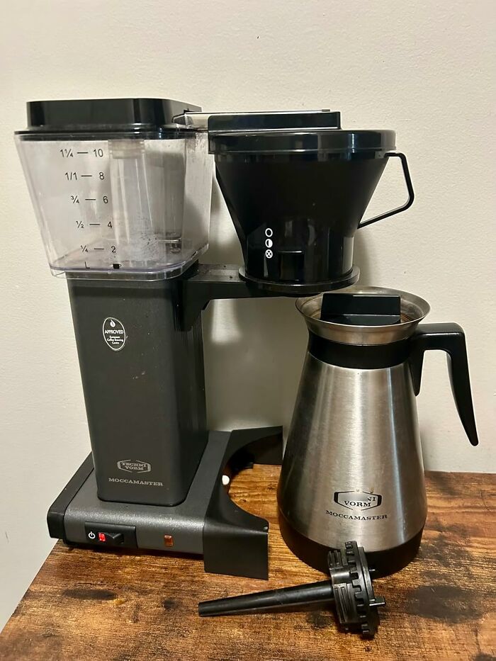Black Friday deals on a stainless steel coffee maker with glass and black components on a wooden table.