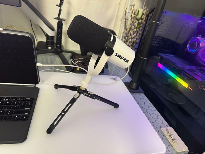 Shure microphone on a tripod stand next to a laptop and gaming PC showcasing Cyber Monday tech deals setup.