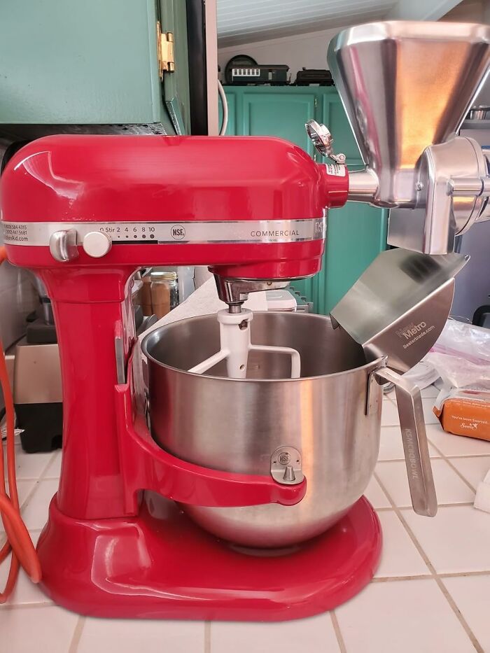 Red commercial mixer with stainless steel bowl and grinder attachment on kitchen counter for Black Friday week deals.