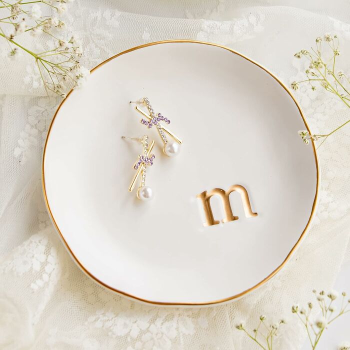 Delicate gold and pearl earrings on a white decorative plate, styled with soft lace and floral accents for aesthetic gifts.