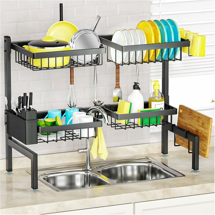 Over-sink dish drying rack with multiple tiers, holding dishes, utensils, and kitchen items in a modern kitchen setup.