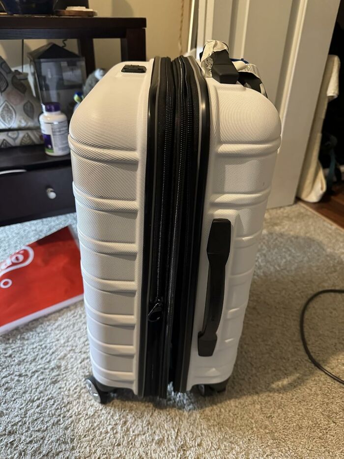 White expandable hard-shell suitcase on carpeted floor, showcasing popular Black Friday week character splurges.