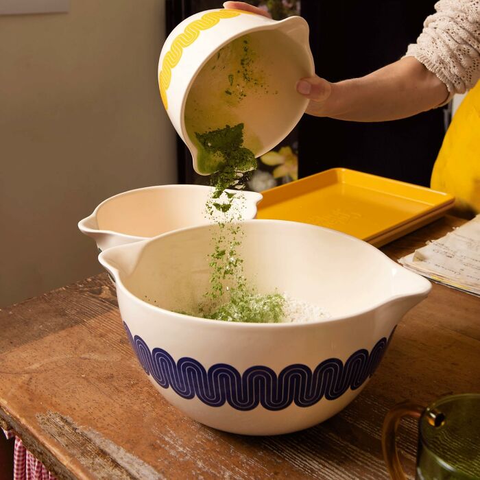 Person pouring green herbs into a vintage mixing bowl as part of Black Friday kitchen deals on cookware and appliances.