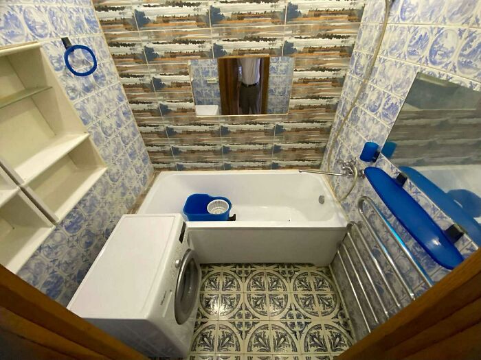 Small bathroom with bathtub, washing machine, and mismatched tile patterns in a wild real estate listing.