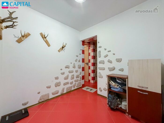 Room with red tiled floor and mounted deer antlers, showing a wild real estate listing with unusual decor.