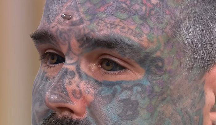 Close-up of a man with extensive face tattoos showing his eyes after getting eyeball tattoos, highlighting the dangerous process. Close-up of a man with extensive face tattoos showing his eyes after getting eyeball tattoos, highlighting the dangerous process.