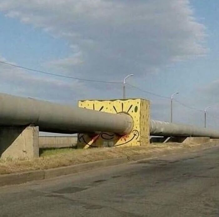 Concrete structure painted with a cartoon face resembling SpongeBob with a large pipe going through its mouth, creative pics that go hard.