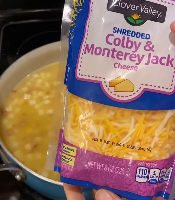 Shredded Colby and Monterey Jack cheese package held over a pot of simmering soup, wild American food creations. Shredded Colby and Monterey Jack cheese package held over a pot of simmering soup, wild American food creations.