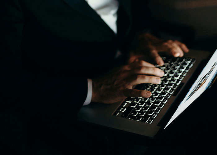 Person in dark setting typing on a laptop, representing terrifying things found online by 31 people.