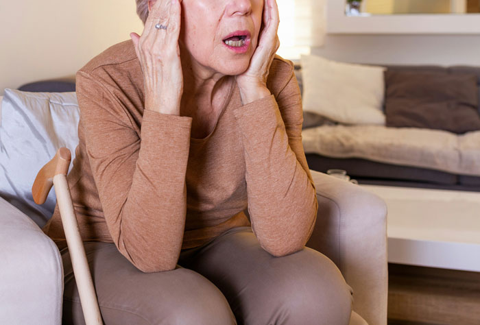 Mujer mayor sentada en sillón con expresión preocupada representando historia de drama familiar caótico.