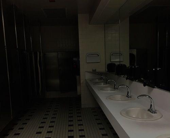 Dimly lit public restroom with sinks and mirrors, creating a spooky atmosphere for the best scary games to play with friends IRL.