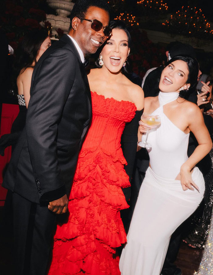 Kris Jenner in a red dress posing with family members at an event, sparking debate on her least favorite.