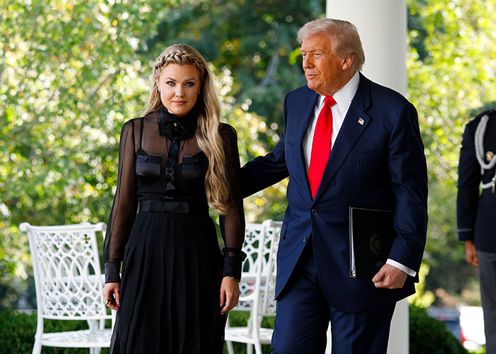 Erika Kirk standing next to a man in a suit outdoors, her gestures sparking wild conspiracy theories about acting.