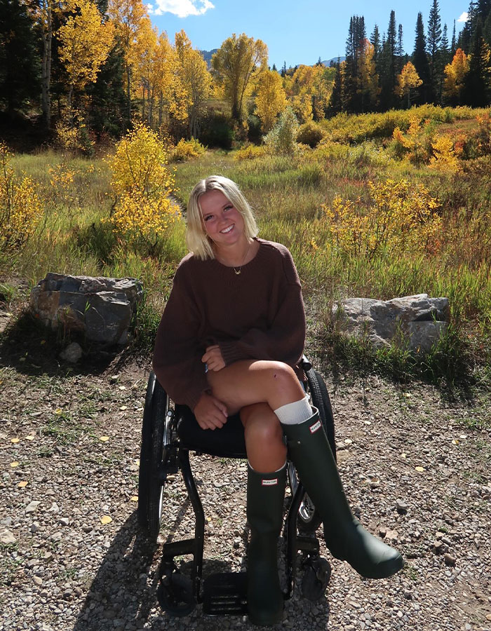 Teen girl in wheelchair outdoors during fall, sharing her emotional story of paralysis after basic mistake on adventure.