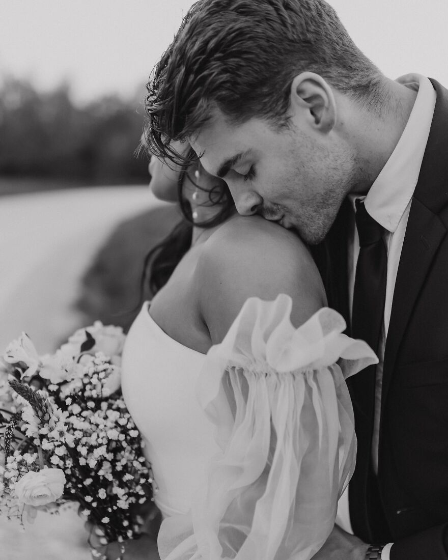 Man in suit gently kissing woman’s shoulder in a romantic moment, illustrating types of kisses in culture and history.