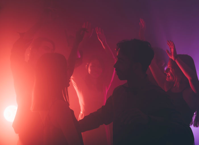 Group of women dancing in colorful light, illustrating key girl code rules shared among friends.