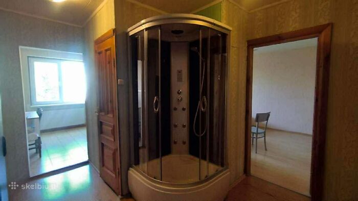 Unusual real estate listing showing a shower unit installed in a hallway between two rooms in a house.