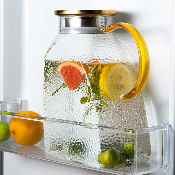 Glass water pitcher with citrus slices stored in fridge door, a practical gift for friends with aesthetic personality traits.