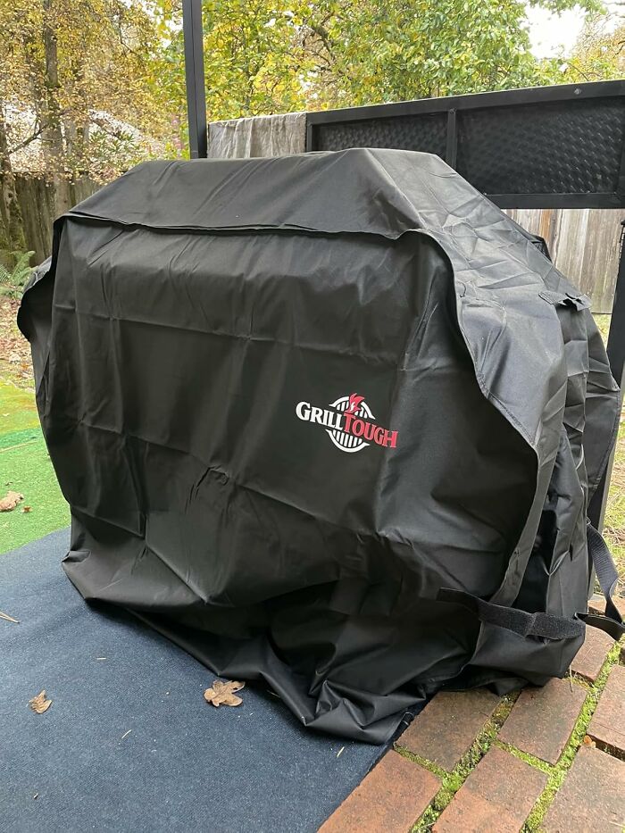 Black Grill Tough cover protecting outdoor grill in a garden, preparing for first freeze and winter weather.