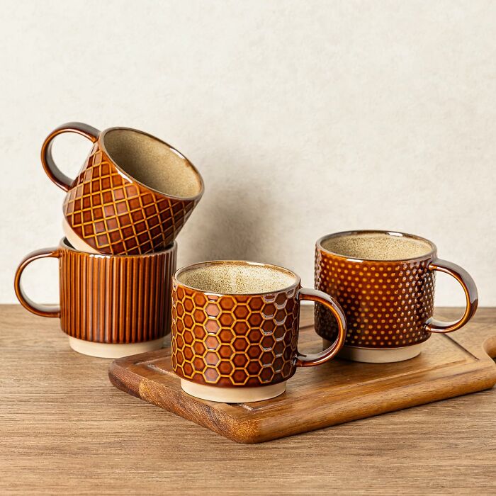 Set of four brown ceramic mugs with textured patterns on wooden surface, ideal gifts for aesthetic personality trait enthusiasts.