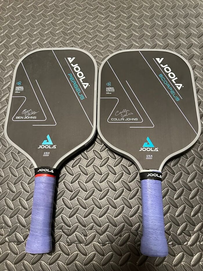 Two JOOLA pickleball paddles with blue grips laid on textured floor, highlighting main character splurges of Black Friday week.