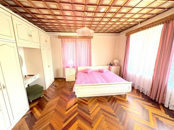 Bright bedroom with vintage white furniture and pink curtains in a wild real estate listing with unique interior design.