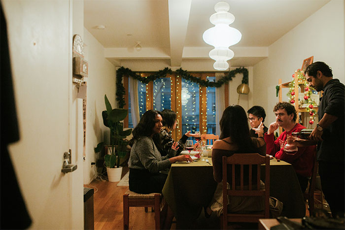 Group of friends at a Friendsgiving dinner with holiday decorations, capturing a tense moment around the table. Group of friends at a Friendsgiving dinner with holiday decorations, capturing a tense moment around the table.