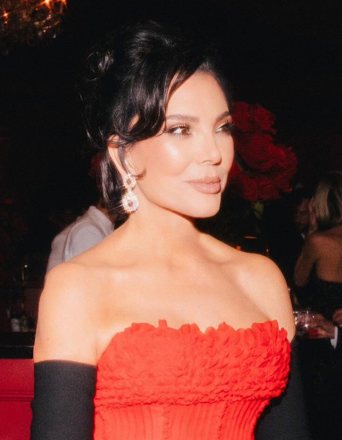 Woman in red strapless dress and sparkling earrings at Kris Jenner's 70th birthday bash guest list event.