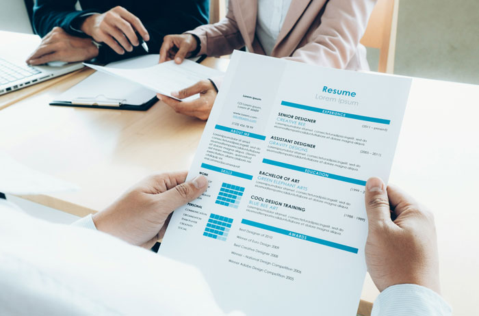 Person holding a resume while two professionals discuss job details in a meeting room, showcasing an Oscar-worthy performance.