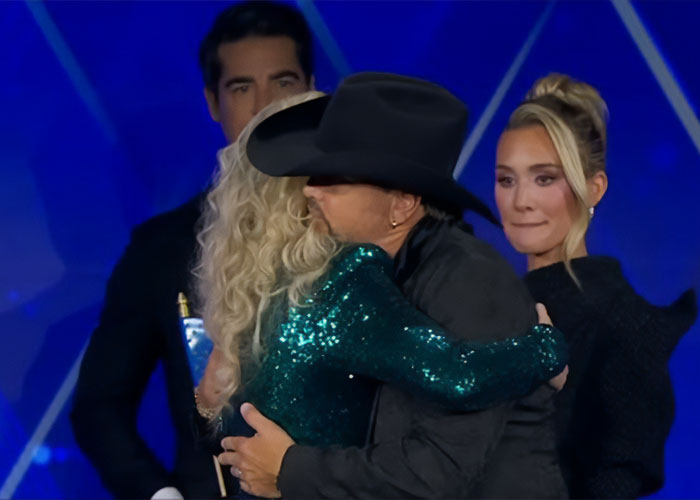 Erika Kirk hugging a man in a black hat while a woman looks on, with acting gestures sparking conspiracy theories.