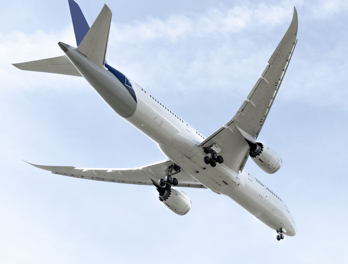 Commercial airplane with landing gear down flying against a cloudy sky, illustrating pilots' terrifying close calls mid-flight.