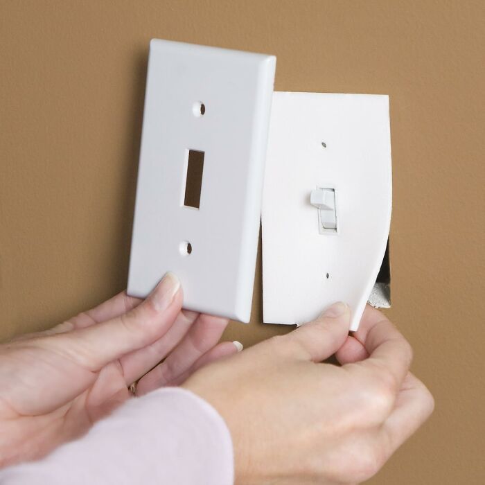 Hands replacing a new switch plate cover on a wall, one of the products to help get your full security deposit back.