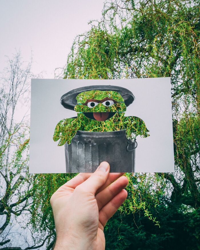 Hand holding paper cutouts of a trash can and character with real-life tree leaves perfectly integrated in background.