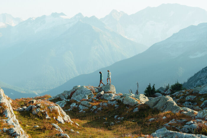 Two hikers exploring rocky terrain with mountainous background, symbolizing a journey to find purpose and direction.