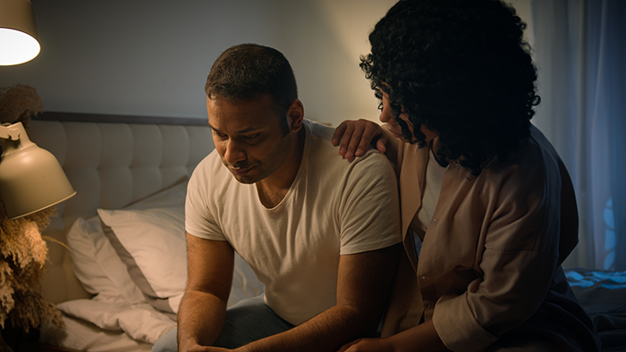 Husband looking upset while wife comforts him at night, discussing daughter and nanny Spanish lessons concerns.