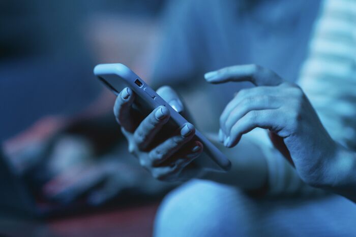 Person holding a smartphone with one hand while using the other hand to navigate, illustrating relationship distance.