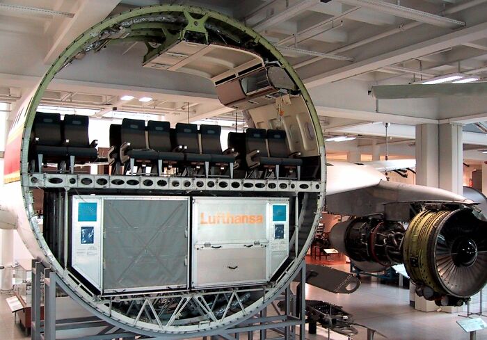 Cross-section of an airplane revealing the insides, including passenger seats and engine components in a museum setting.