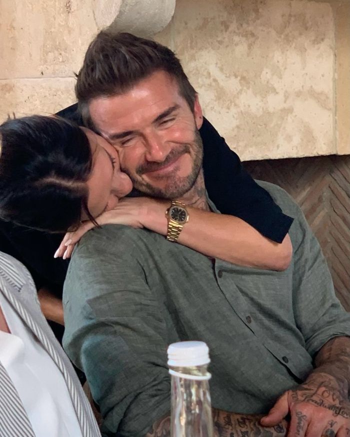 Victoria Beckham embraces David Beckham smiling warmly after David receives Sir title in a cozy indoor setting. Victoria Beckham embraces David Beckham smiling warmly after David receives Sir title in a cozy indoor setting.