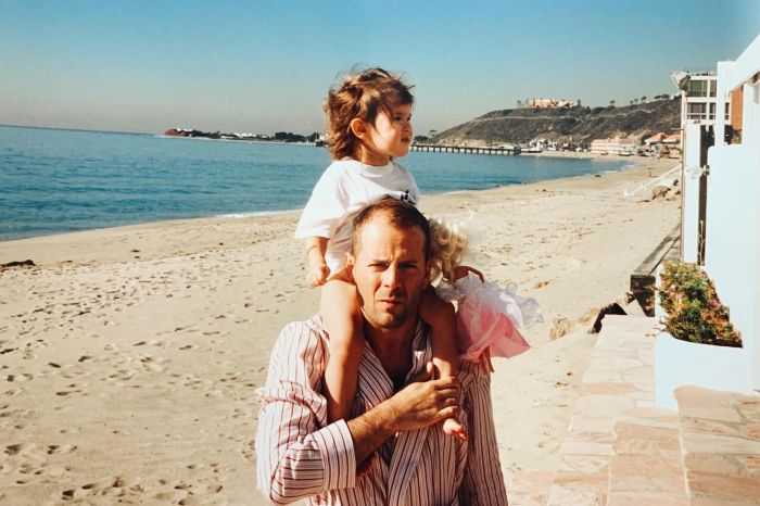 Bruce Willis with a child on his shoulders at the beach, illustrating a family moment amid dementia update.